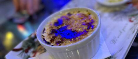 Un postre en un tazón blanco sobre una mesa con servilleta estampada con flores.
