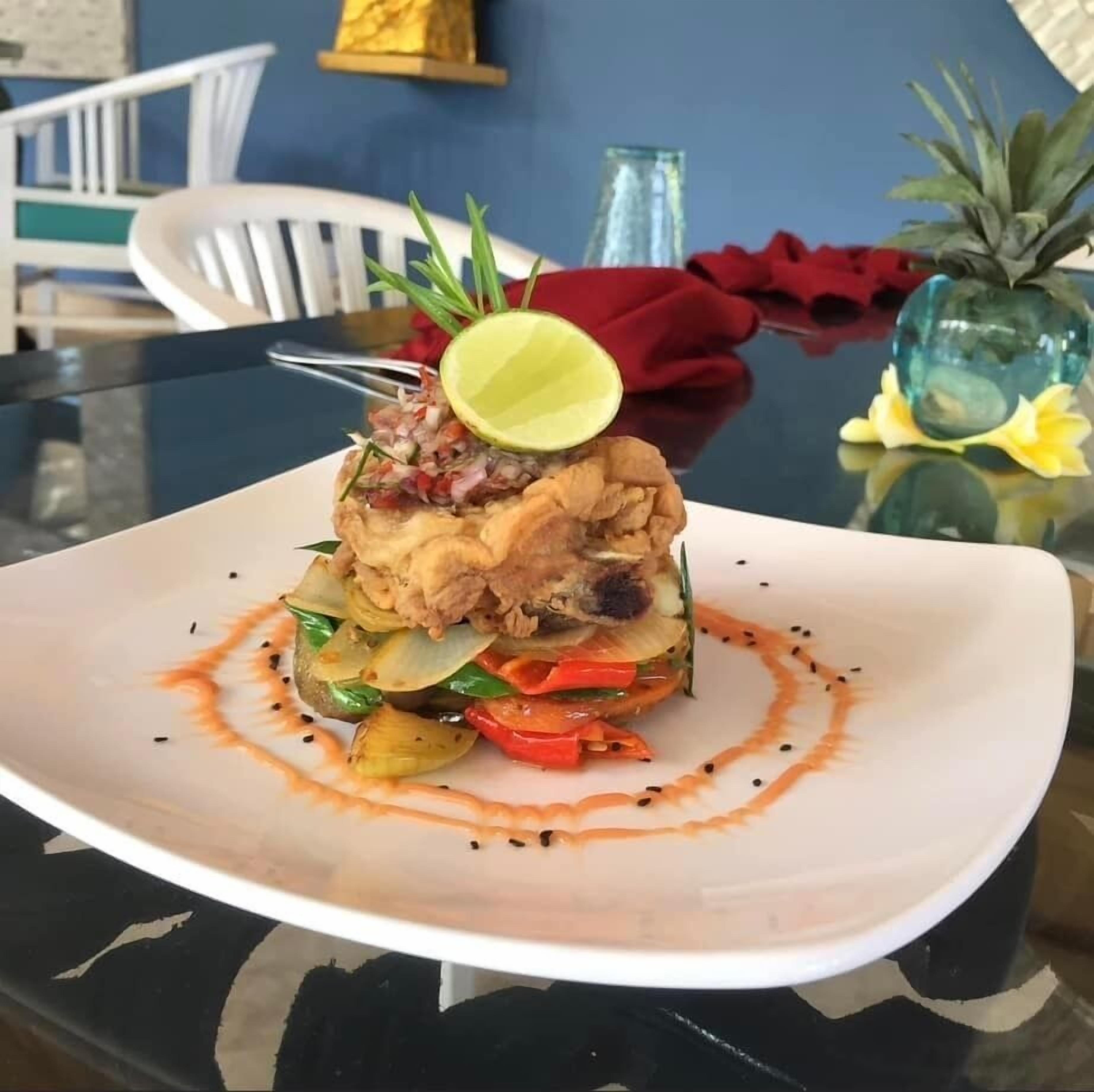 A plated dish with a variety of vegetables and a lime wedge on top.