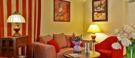A living room with a checkered sofa, a red armchair, a wooden coffee table, and two lamps.
