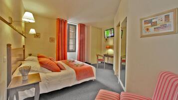 Una habitación de hotel con una cama, un escritorio, una silla, un televisor y un cuadro en la pared.