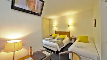 A hotel room with two beds, a TV, a desk with a lamp, and a chair.