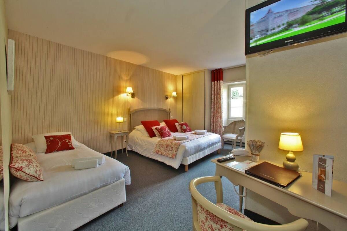 Habitación de hotel con dos camas, un escritorio, un televisor y una ventana con cortinas.