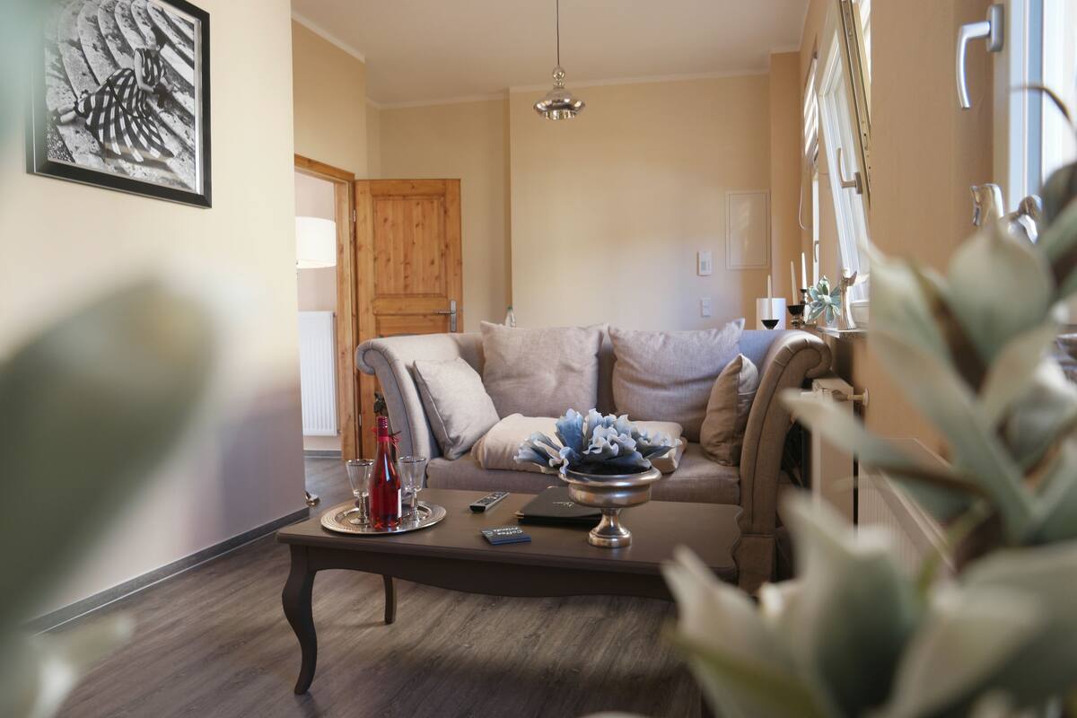 Un salon avec un canapé, une table basse et une porte au fond.