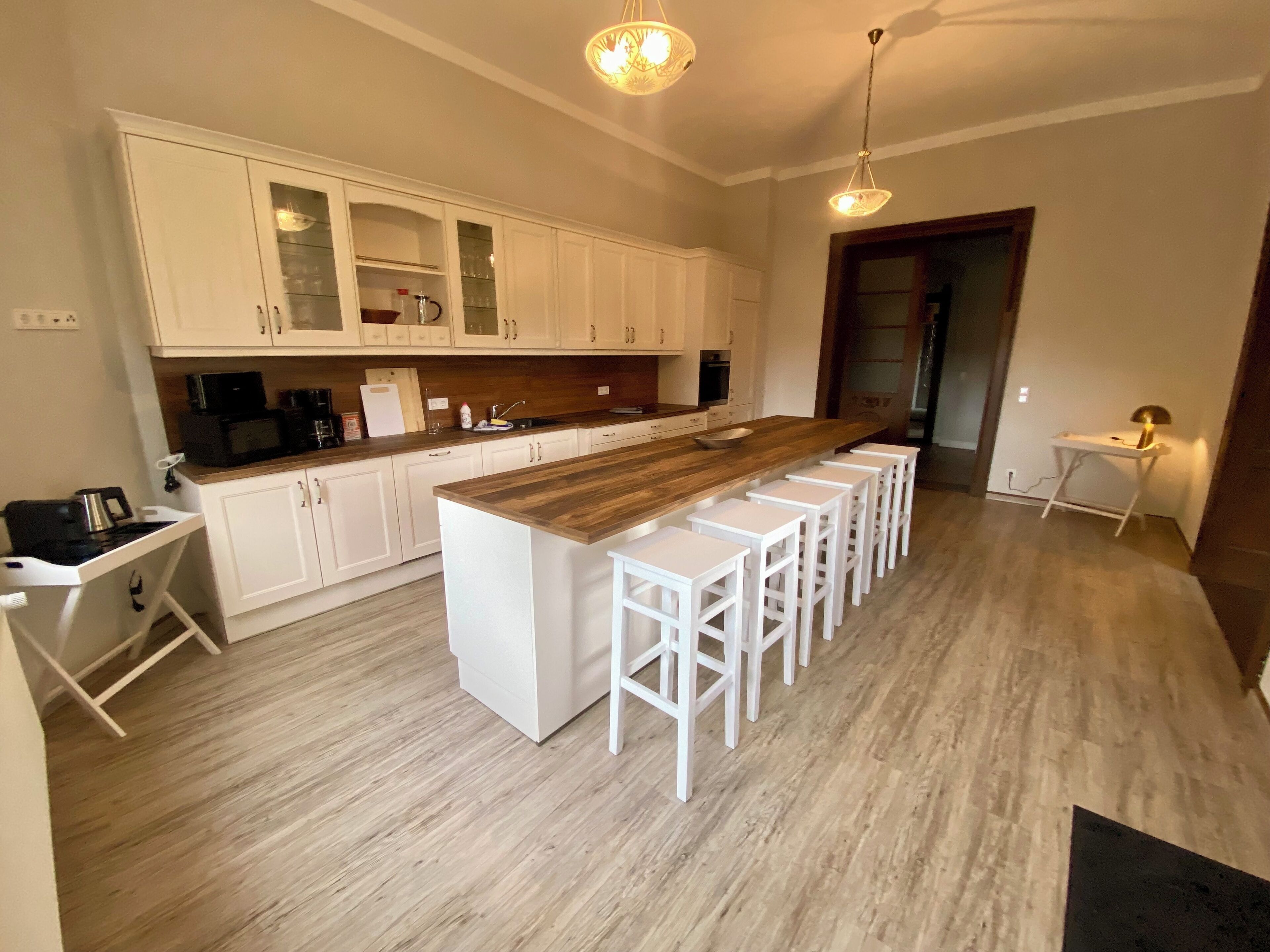 A modern kitchen with white cabinetry, a wooden island with bar stools, and pendant lighting.