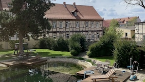 Une cour avec une piscine, du mobilier d’extérieur et un bâtiment doté d’un toit en tuiles.