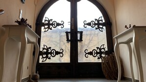 Une entrée imposante, avec une porte en arc de cercle, un lustre et deux petites tables d’appoint blanches.