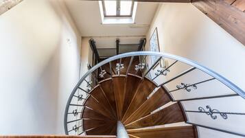 Eine Wendeltreppe mit hölzernen Stufen und Metallgeländern, die zu einer oberen Etage führt.