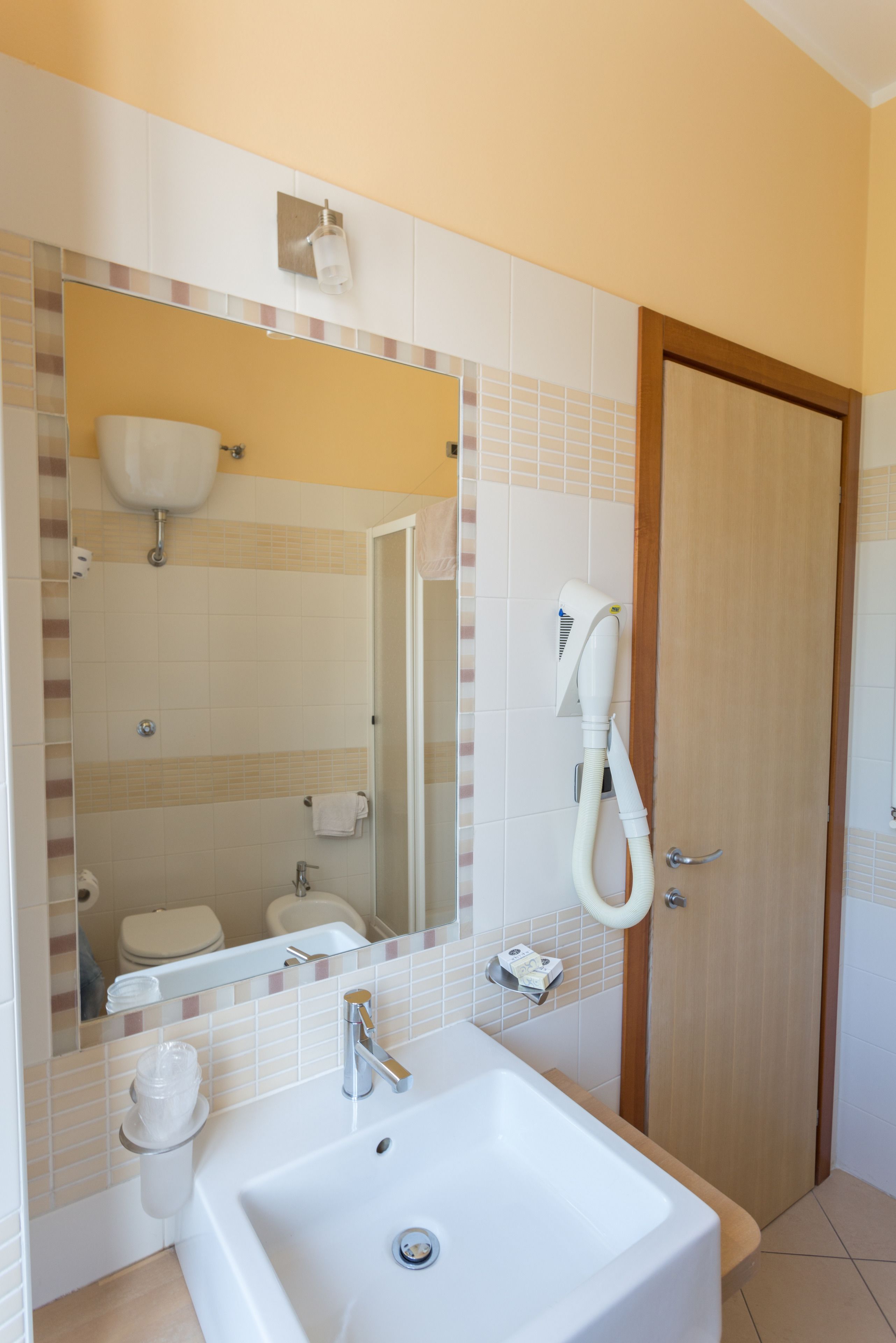 A bathroom with a white sink, a mirror, a towel rack, and a shower area.