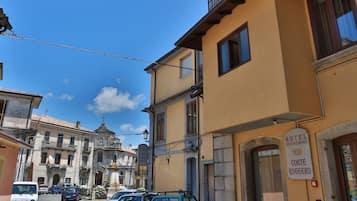 Una calle con coches aparcados y un hotel llamado "Hotel Conte Ruggero", con un cartel que indica "Hotel Bed & Breakfast".