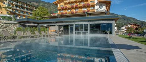 A hotel with a large outdoor pool, wooden balconies, and mountain views.