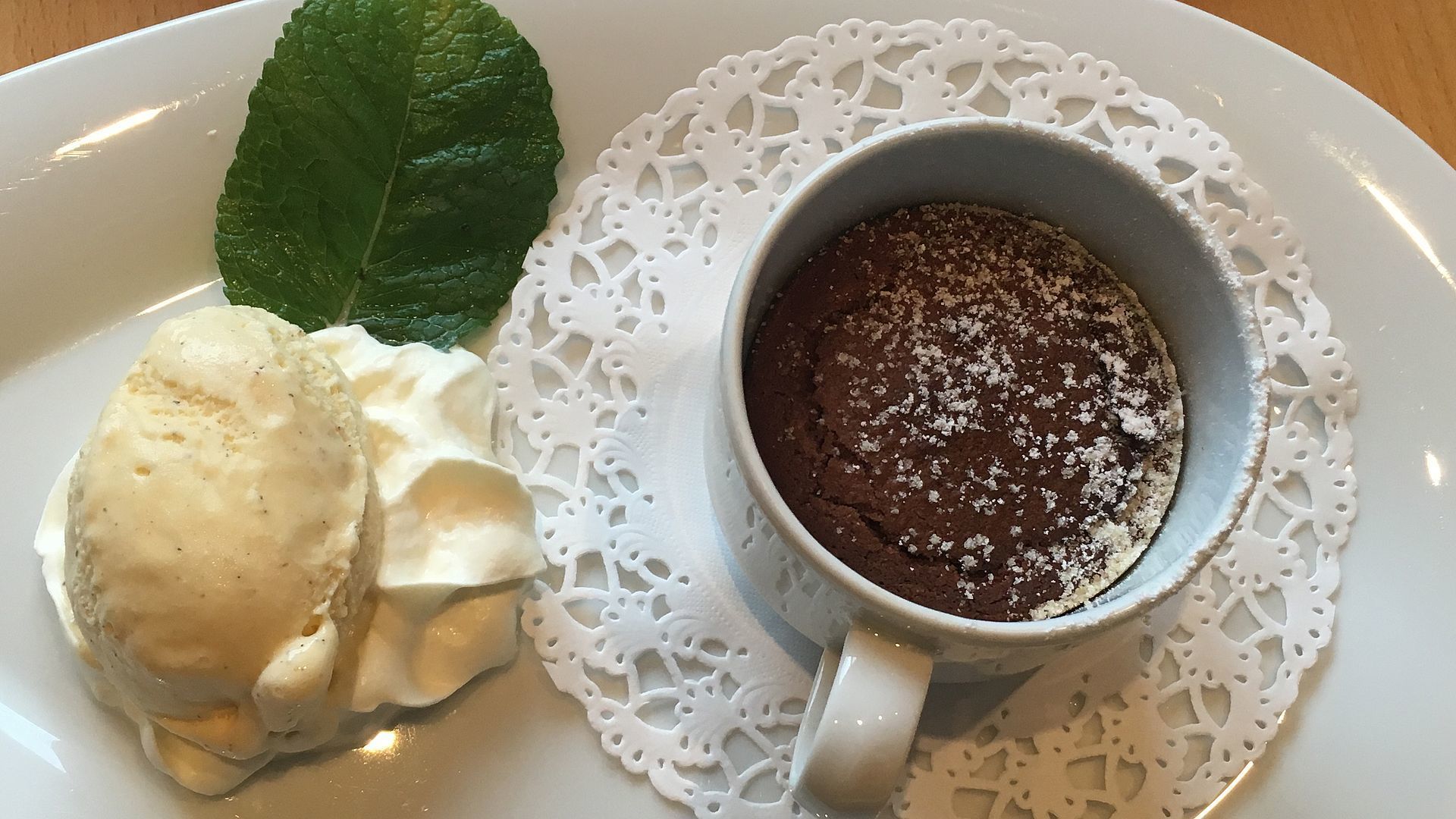 Um prato de sobremesa com um bolo de lava de chocolate e uma bola de sorvete de baunilha.