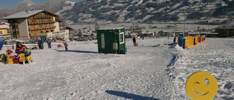 Estación de esquí nevada con un hotel, remontes y montañas al fondo.