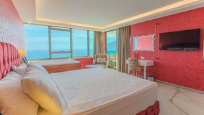A hotel room with a large bed, a desk, a chair, a TV, and a view of the sea. - Wien Star Hotel (Alanya)