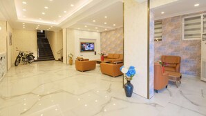 A spacious lobby with a marble floor, a staircase, a sofa set, a television, and a motorcycle. - Wien Star Hotel (Alanya)