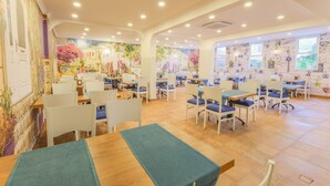 A spacious dining area with tables and chairs, featuring a mural with floral and architectural elements on the walls. - Wien Star Hotel (Alanya)