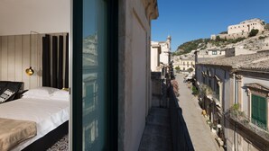 A narrow balcony with a bed and a view of a historic building. - Palazzo Conti Camere & Suite (Scicli)