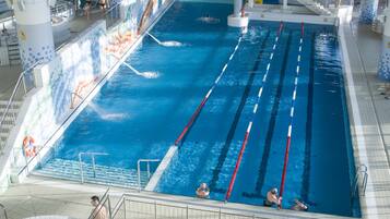 An indoor swimming pool with multiple lanes, a slide, and a hot tub area.