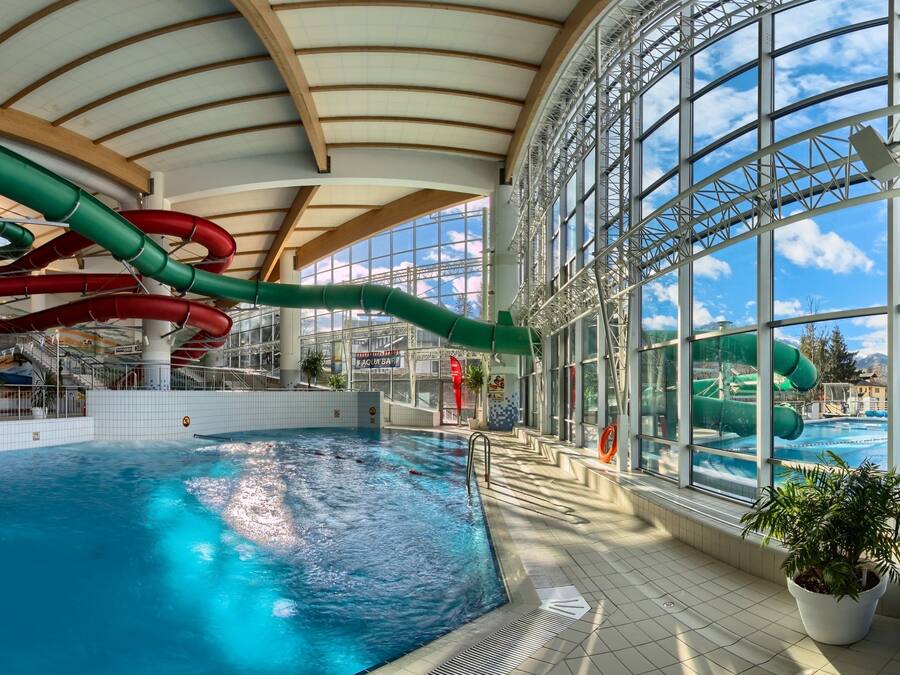 Une piscine intérieure dotée de plusieurs toboggans et d’une grande baie vitrée donnant sur l’extérieur.