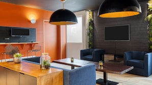 Ein modernes Wohnzimmer mit einem Holztisch, blauen Sofas und einem an der Wand montierten Fernseher.