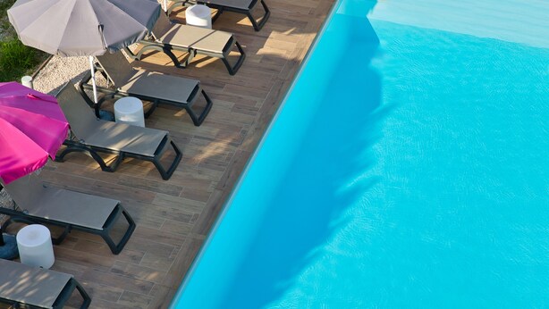Ein Poolbereich mit Liegestühlen und Sonnenschirmen.