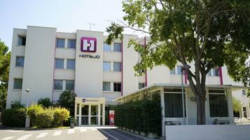 Un hotel con fachada moderna, un logotipo destacado y un letrero que indica afiliación a la cadena 'Best Western'.