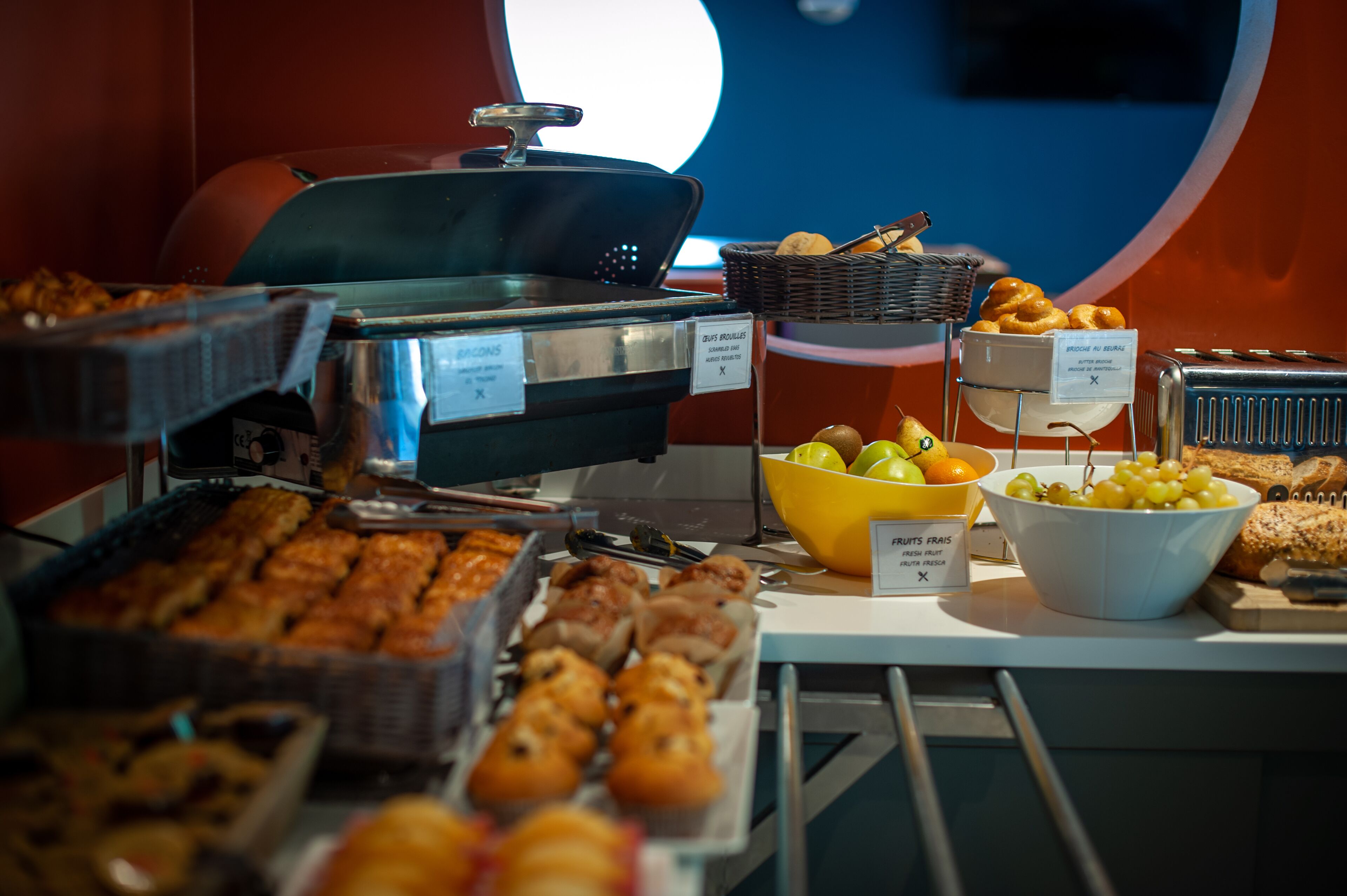 A buffet with various food items including pastries, fruits, and bread.