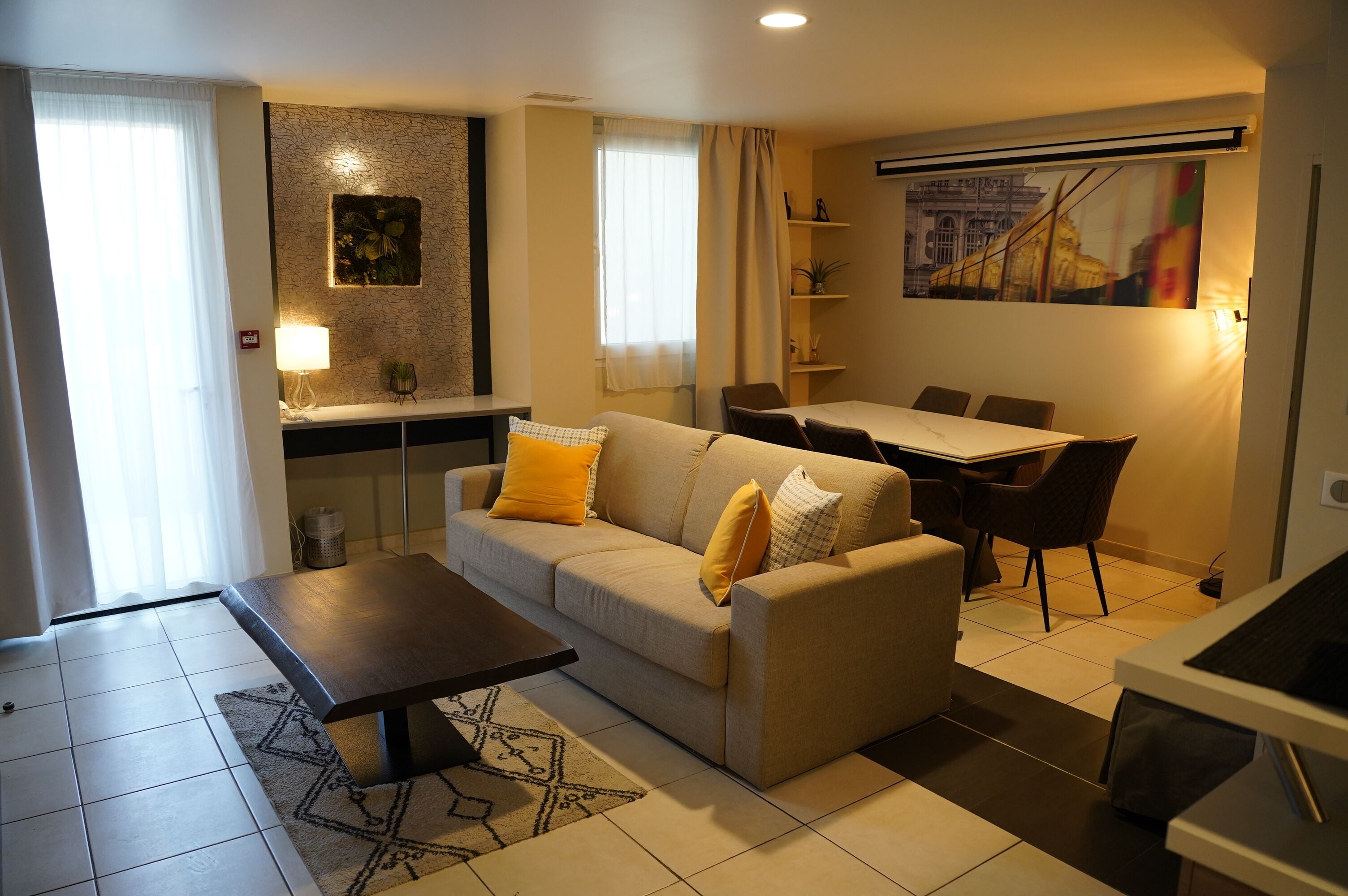 A living room with a sofa, coffee table, dining table, chairs, and a TV.