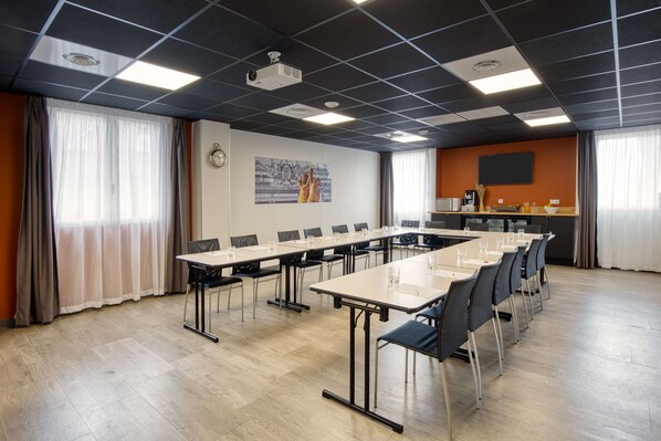 Una sala de conferencias con una larga mesa, sillas, un proyector y un reloj en la pared.