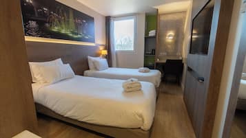Hotelkamer met twee bedden, een bureau, een stoel, een televisie en een schilderij aan de muur.