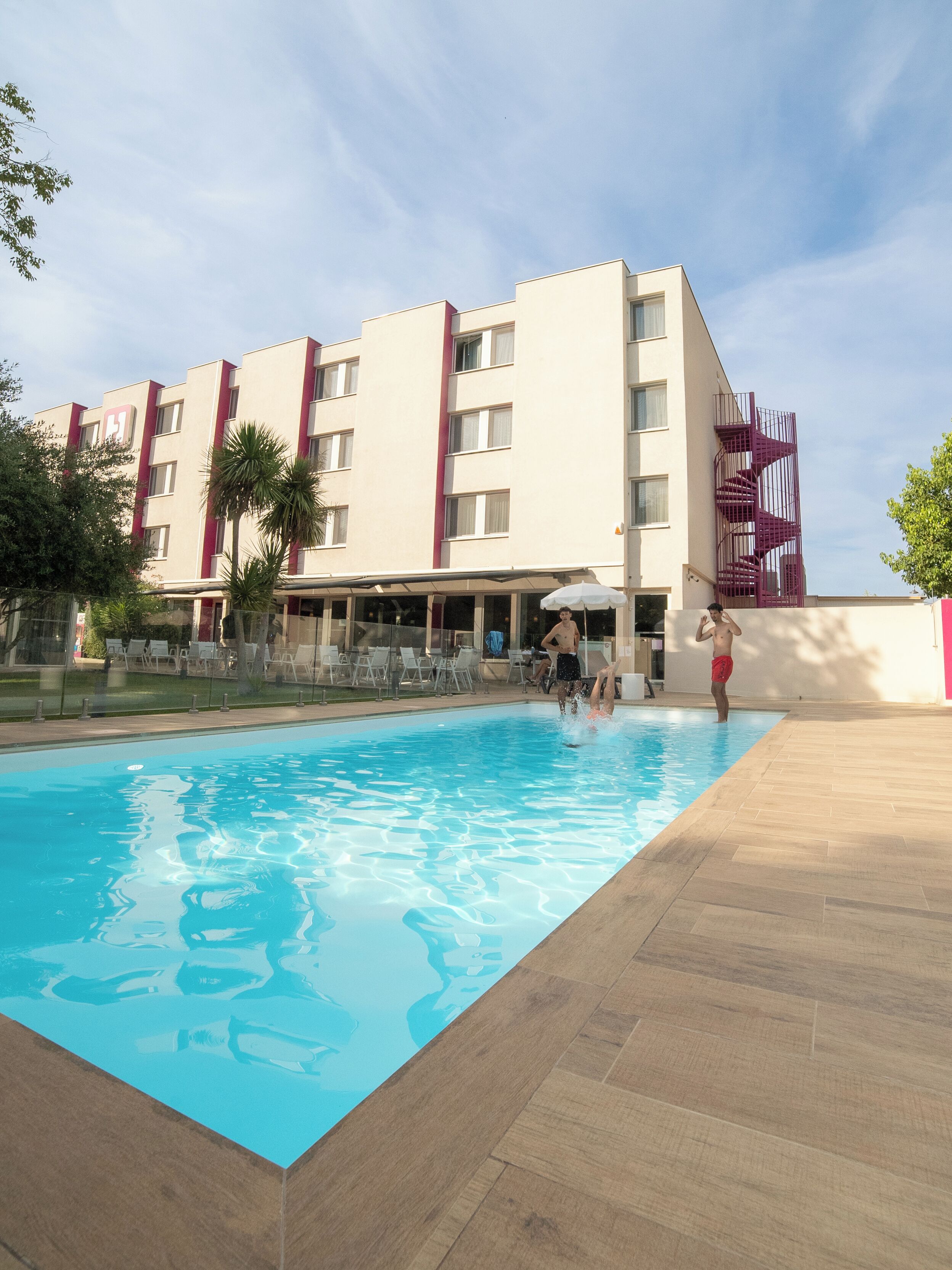 A hotel with a swimming pool, outdoor seating, and a modern building design.