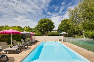 Una piscina al aire libre de temporada, sombrillas