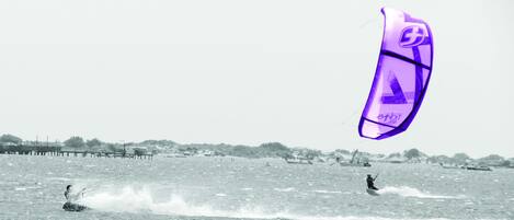 A beach with a pier and a person kiteboarding.