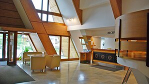 Eine großzügige Lobby mit hoher Decke, Holzbalken und einer Rezeption mit dem Schild "RECEP".