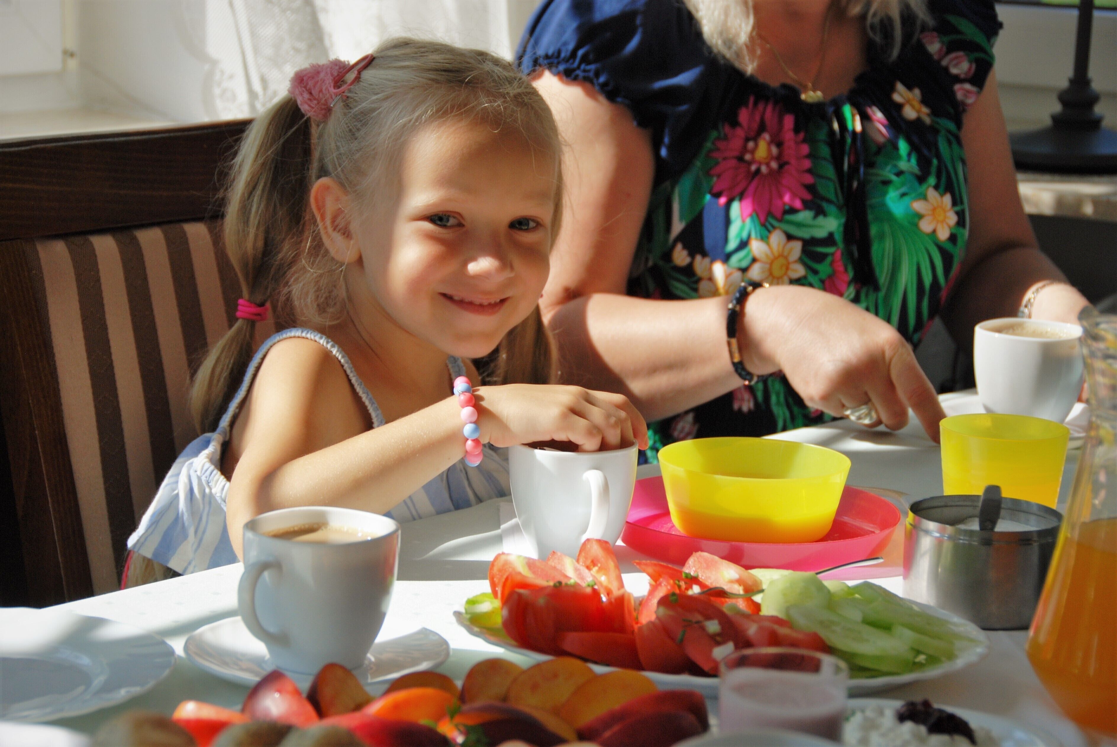 A dining table with a plate of fruit, a cup of coffee, and a yellow bowl.