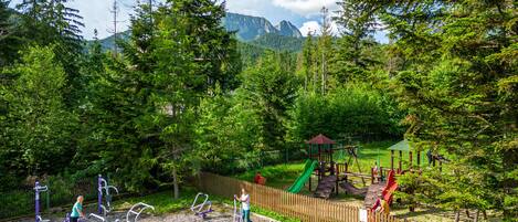 A playground with exercise equipment, a slide, and a wooden fence.