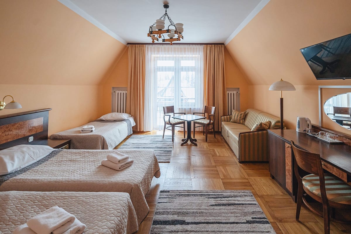 Une chambre d’hôtel avec deux lits, un canapé, une table à manger et un téléviseur.