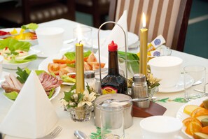 Ein Tisch ist für eine Mahlzeit gedeckt, mit verschiedenen Gerichten, Gewürzen und einer Flasche Mineralwasser.