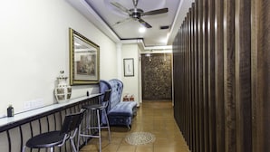 Un couloir étroit doté d’un sol carrelé, d’un ventilateur de plafond, d’un coin bar avec des tabourets et d’un mur orné de motifs.
