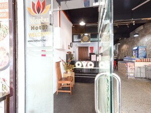L’entrée de l’hôtel Norbu, avec un comptoir d’accueil, une chaise en bois et un panneau indicateur.