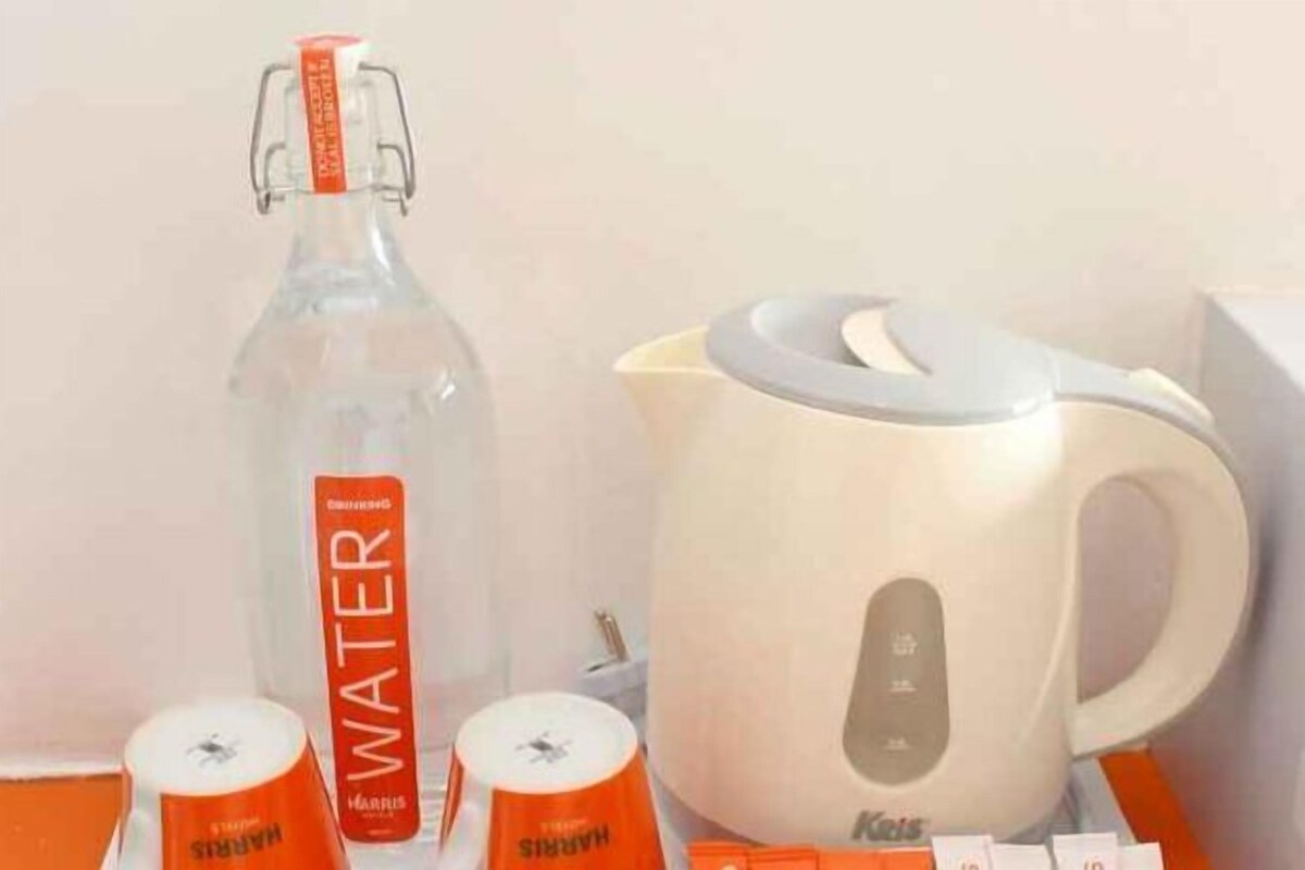 A water bottle, a kettle, and two cups on a table.