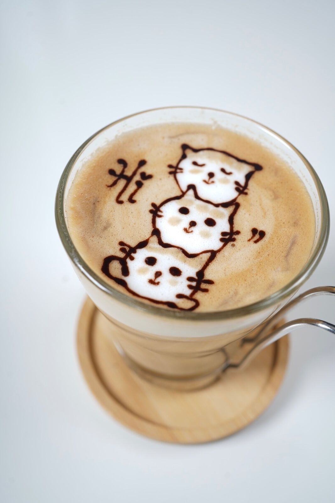 A glass of coffee with a cat design on the foam.