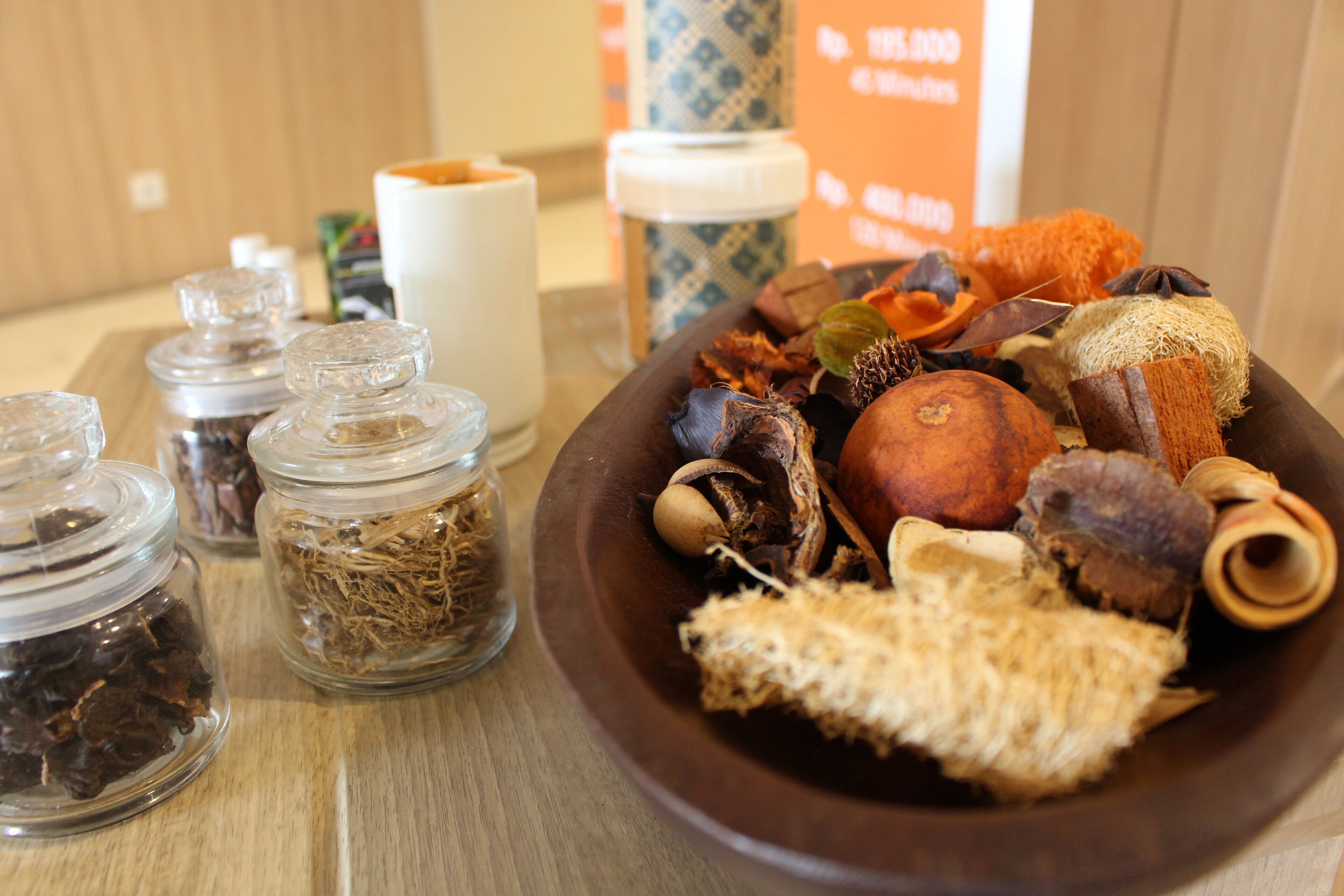 Una mesa de madera con un cuenco de plantas y especias secas, y dos tarros de vidrio con hierbas secas.