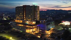 Un hotel de varios pisos con un letrero llamativo, un bar en la azotea y un estacionamiento.