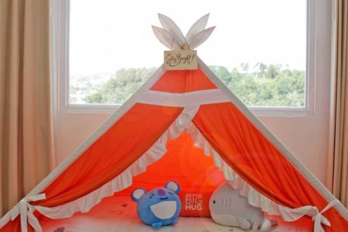 Una habitación con ventana, una estructura tipo tienda de campaña roja y blanca, y dos peluches.