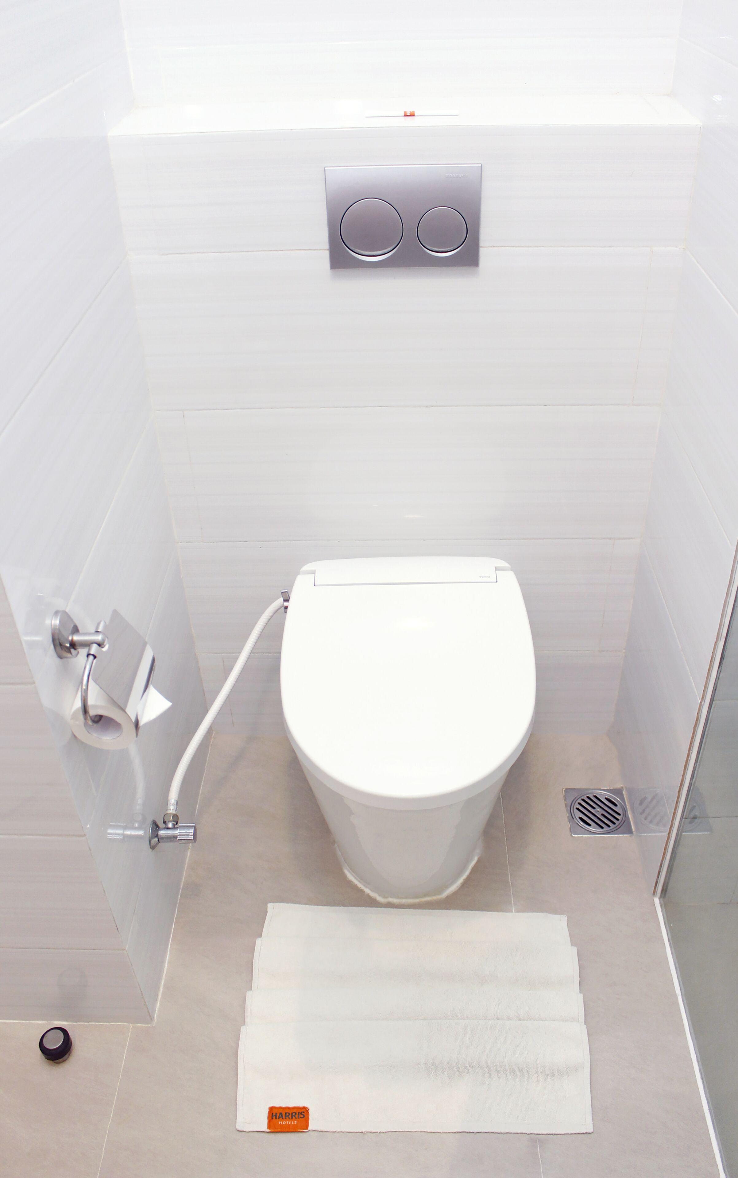 A modern bathroom with a toilet, a shower, and a towel rack.