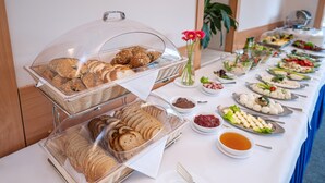 Un buffet proposant une variété de plats, notamment du pain, des pâtisseries, des salades et des sauces.