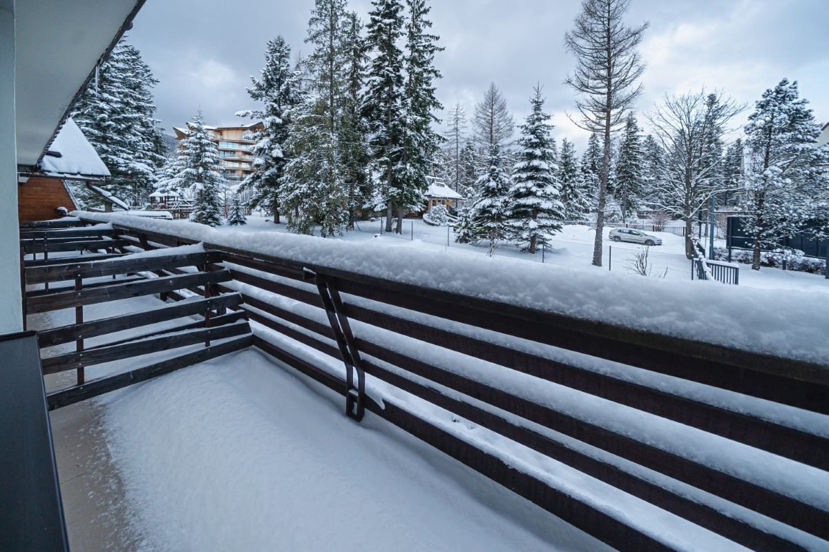 A snowy outdoor area with a wooden staircase leading to a building.