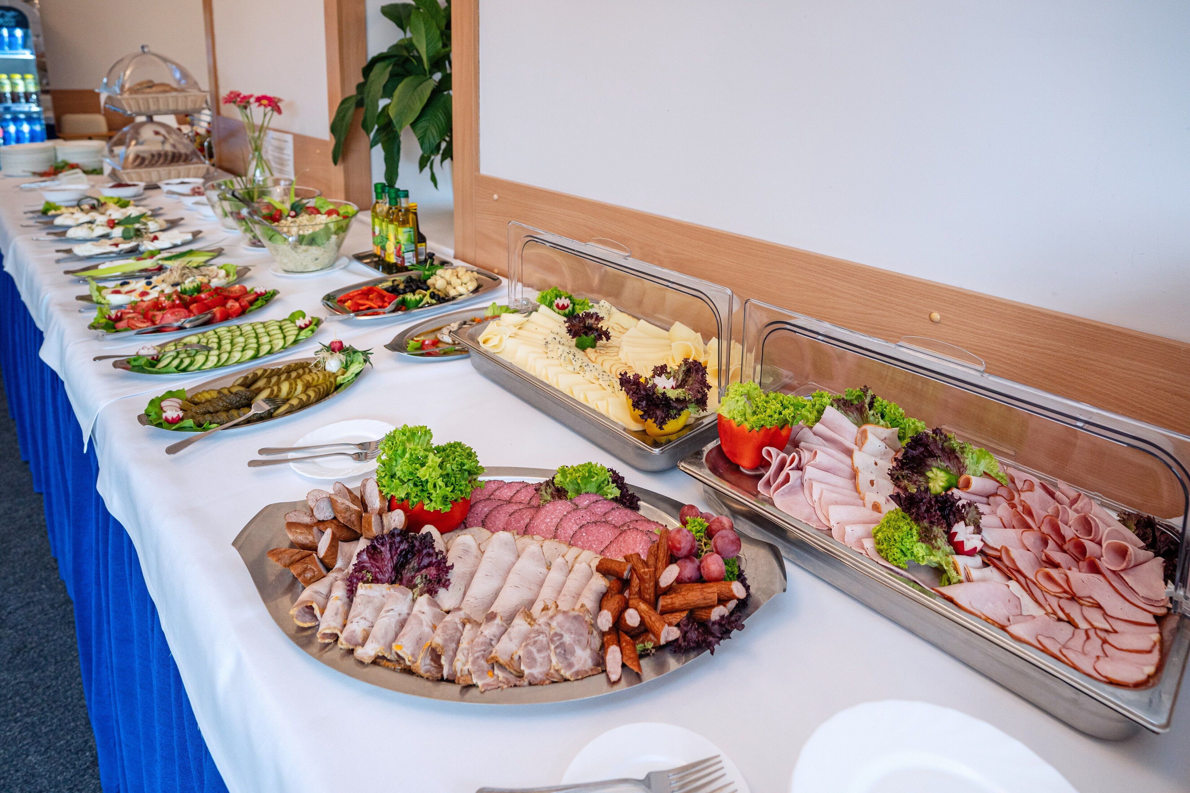 Ein reichhaltiges Buffet mit verschiedenen Speisen, darunter Fleisch, Käse und Gemüse.