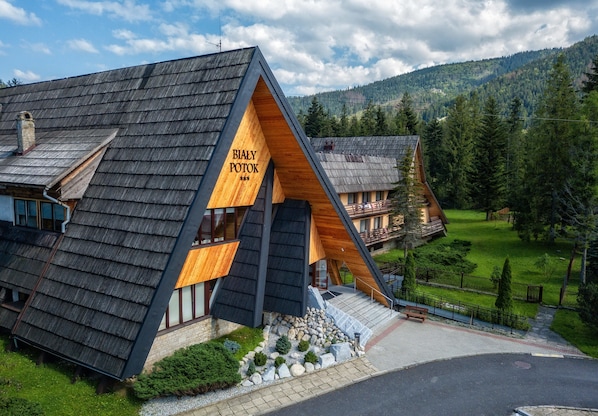 A modern building with a sloped roof, a wooden facade, and a sign reading "BIALY POTOK".