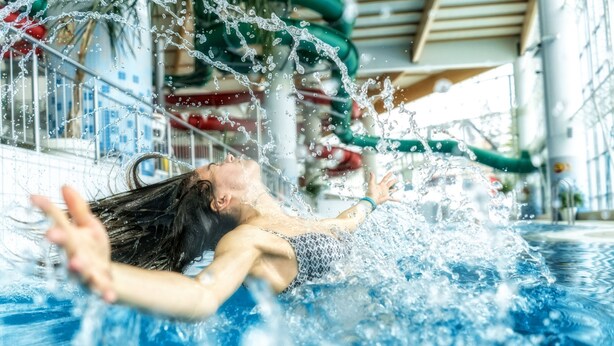 Une personne nage dans une piscine, et l’eau éclabousse autour d’elle.